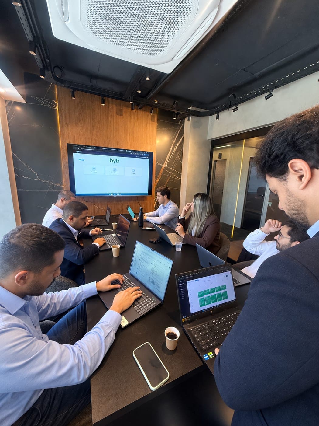 Equipe da ByBrain reunida em volta da mesa com notebooks